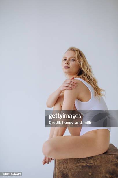 female gymnast in a white leotard sitting on a wooden block - gympak stockfoto's en -beelden