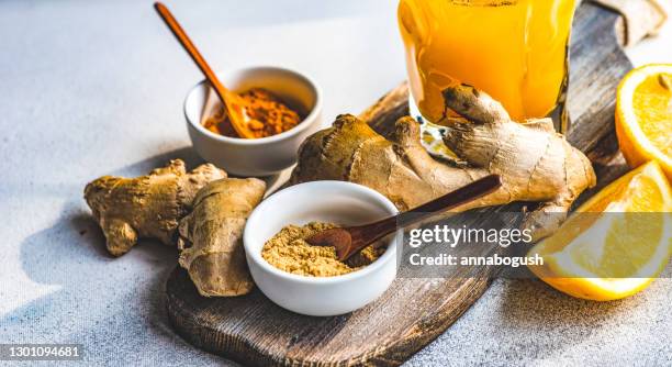 fresh turmeric, ginger and orange drink with ingredients on a table - ショウガ ストックフォトと画像