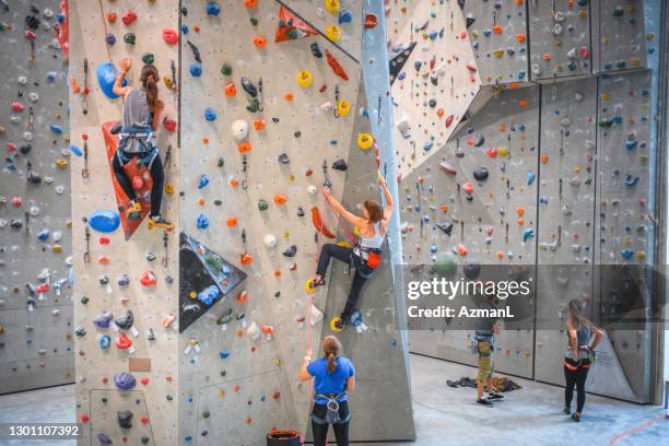 wide angle view of sportspeople ascending climbing wall - climbing wall stock pictures, royalty-free photos & images