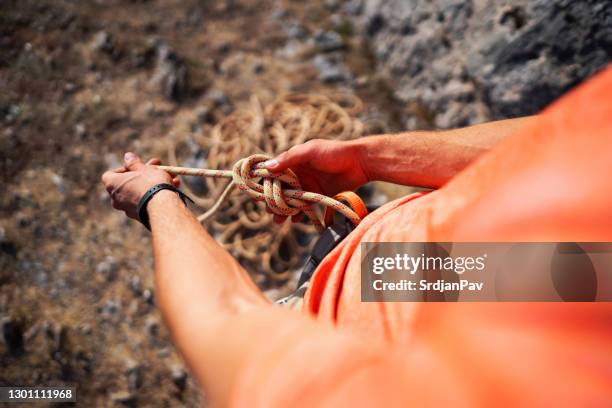 hochwinkelansicht eines unkenntlichen kletterers, der sich beim binden des knotens mit kletterseil vorbereitet - knoten stock-fotos und bilder