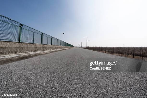 road next to a fence - prison fence stock pictures, royalty-free photos & images