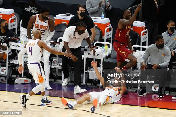Devin Booker of the Phoenix Suns falls to the court after hitting a three-point shot and drawing a foul from Taurean Prince of the Cleveland...