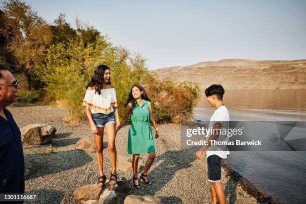 smiling and laughing family hanging out by river during summer road trip - eltern sonnenbrille sonne lachen stock-fotos und bilder