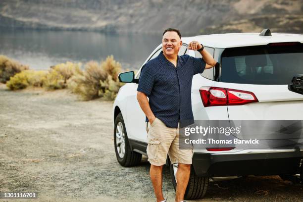 smiling mature man standing next to car during road trip - naast stockfoto's en -beelden