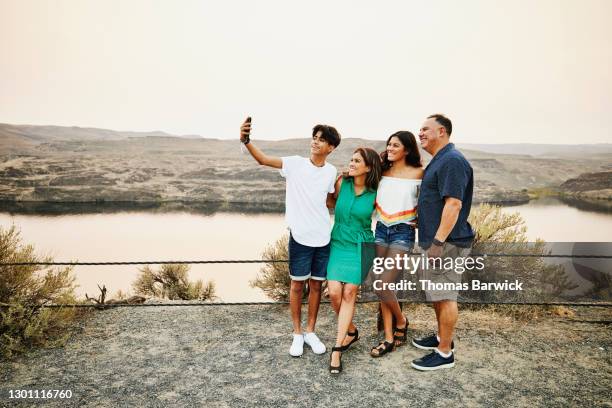 smiling family taking selfie with smart phone during summer vacation - open day 4 stockfoto's en -beelden