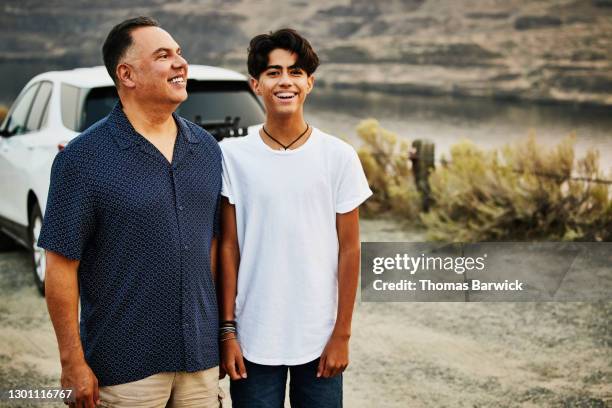 smiling father and son standing next to each other during family road trip - boy river looking at camera stock pictures, royalty-free photos & images