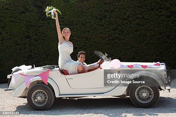 newlyweds leaving for honeymoon in vintage car - bride and groom wedding car stock pictures, royalty-free photos & images