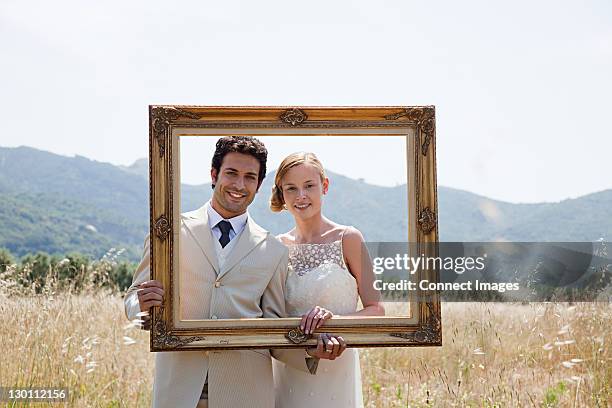 newlyweds holding vintage picture frame - front on groom and bride stock pictures, royalty-free photos & images