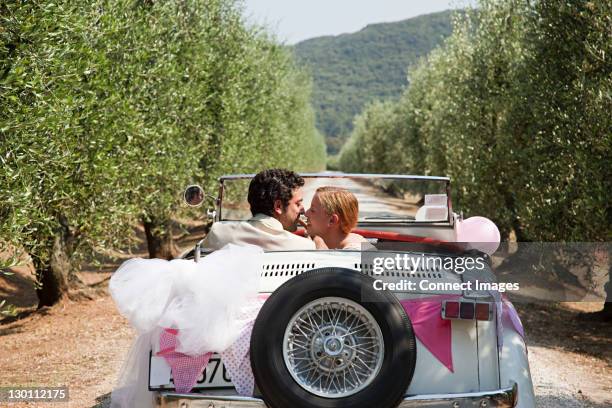 newlyweds kissing in classic car - bride and groom wedding car stock pictures, royalty-free photos & images