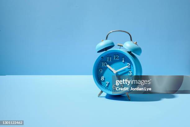 blue alarm clock on blue background - style studio day 1 stock-fotos und bilder