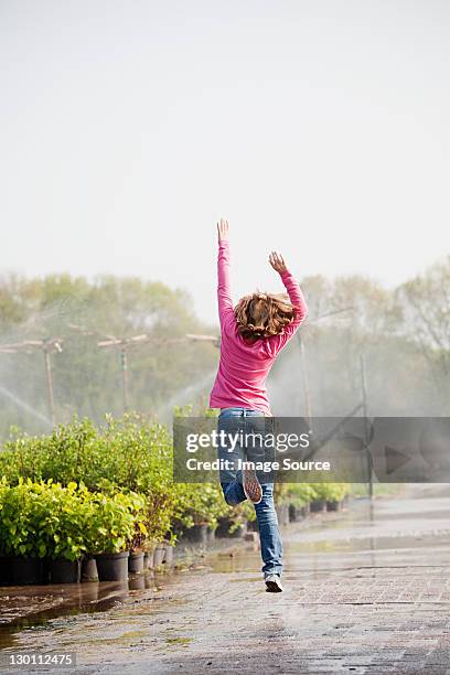 girl skipping along path in plant nursery - skip stockfoto's en -beelden