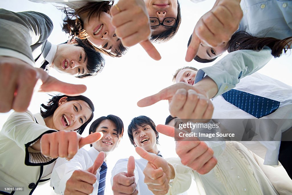 Businesspeople in a circle with thumbs up