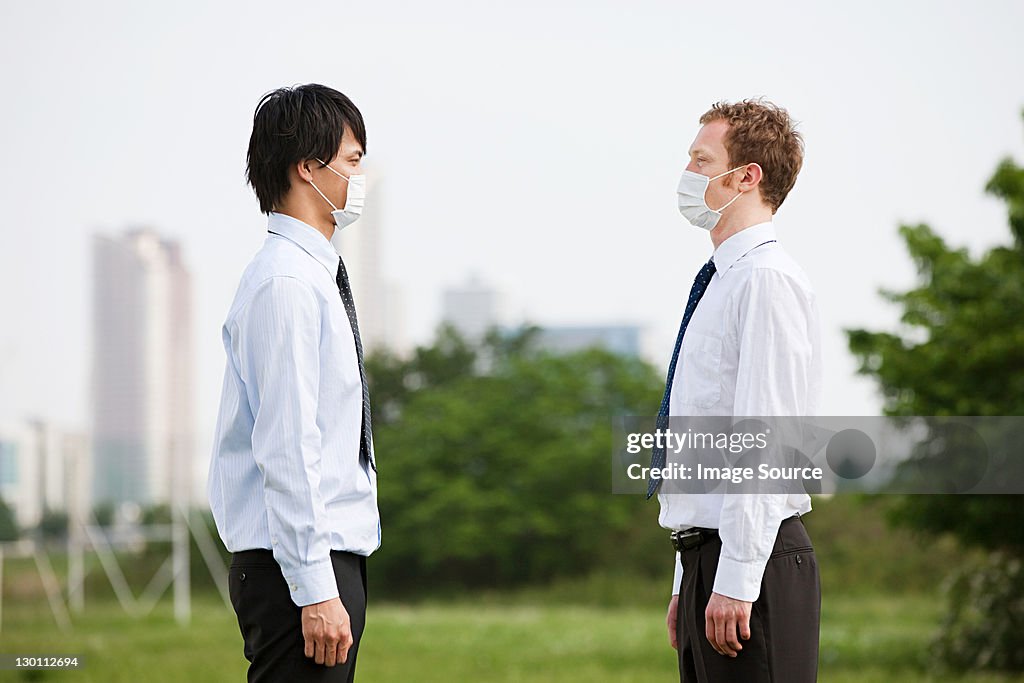 Dois Empresário vestindo a poluição máscaras, cara a cara