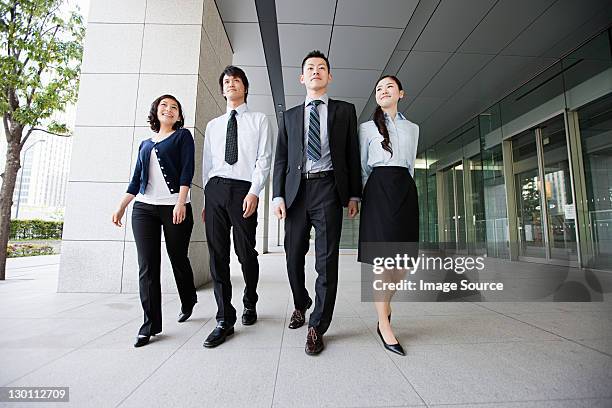 four businesspeople on sidewalk - four people walking stock pictures, royalty-free photos & images