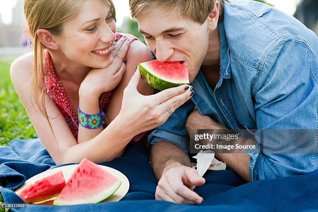 Young woman feeding man watermelon