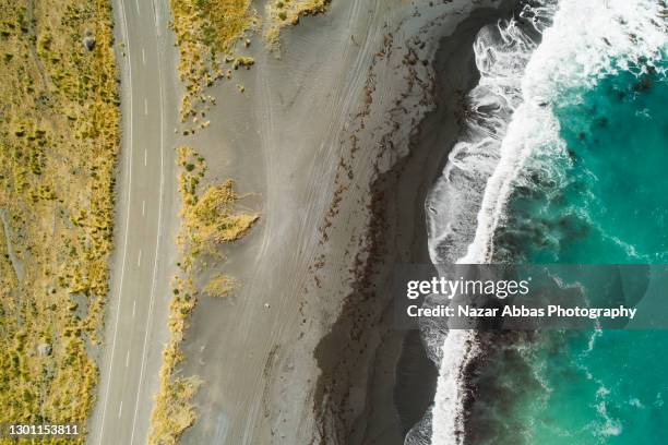 close up of water's edge along with a coastal road. - gravel stock pictures, royalty-free photos & images