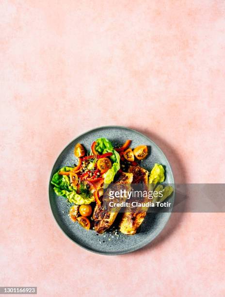 plate of grilled chicken with fresh salad on peach background - gourmet chicken stock pictures, royalty-free photos & images