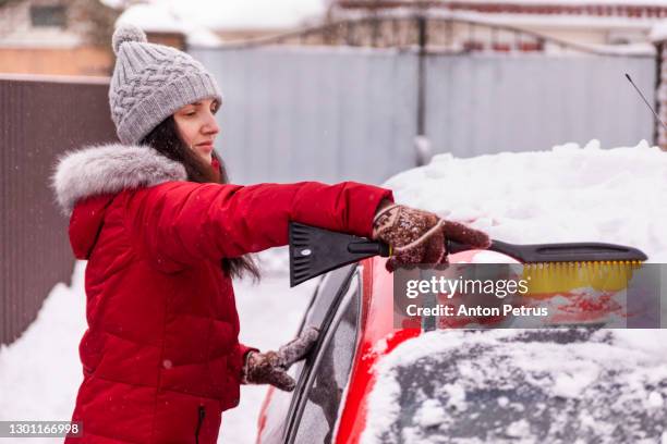 woman cleaning snow from car after snowfall - winter car window stock pictures, royalty-free photos & images