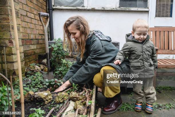 toddler keeping mother company as she gardens in backyard - women gardening stock pictures, royalty-free photos & images