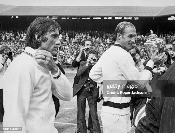 Stan Smith of the United States poses for photographs holding the Gentlemen's Singles Trophy beside the defeated Ilie Nastase following their Men's...