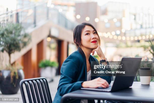 young woman using laptop at sidewalk cafe - digital business london stockfoto's en -beelden