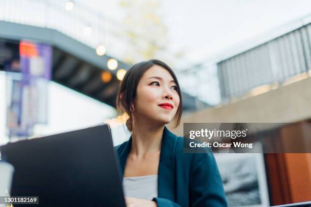 young woman using laptop at sidewalk cafe - flexible work stock-fotos und bilder