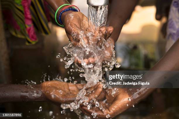 stream of water pouring into children’s hands in southern burkina faso. - hand washing stock pictures, royalty-free photos & images