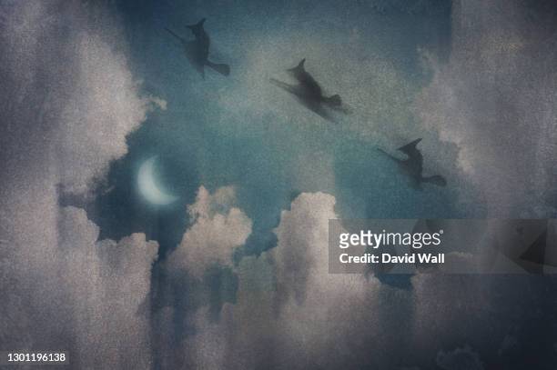 three witches flying on broomsticks. silhouetted against the night sky. surrounded by clouds. with a vintage, grunge edit. - bruja fotografías e imágenes de stock