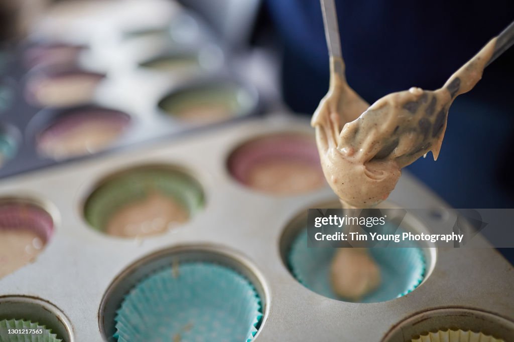 Cake mixure being spooned into a cupcake case