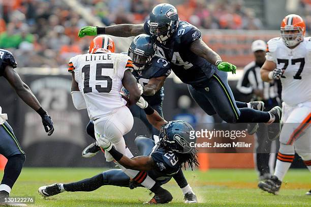 Defenders Earl Thomas, Kennard Cox and Anthony Hargrove of the Seattle Seahawks tackle wide receiver Greg Little of the Cleveland Browns at Cleveland...