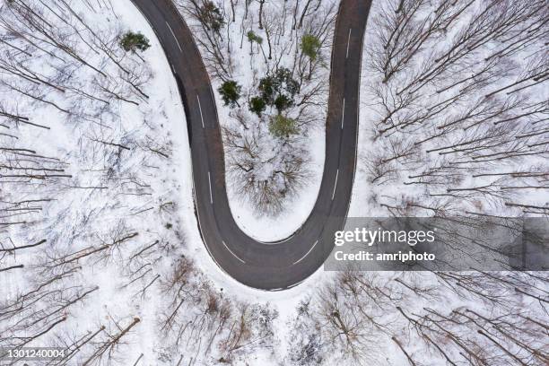 curva aérea de carretera de campo en bosque cubierto de nieve desde arriba - letra u fotografías e imágenes de stock