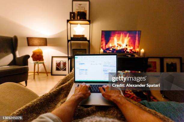 man sitting on the couch in the living room and working on a laptop, personal perspective view - tartan stock pictures, royalty-free photos & images