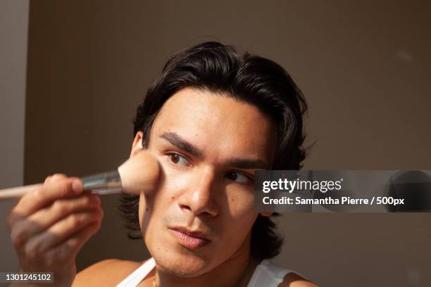 mixed race lgbtq man using makeup,toronto,ontario,canada - man make up stock pictures, royalty-free photos & images