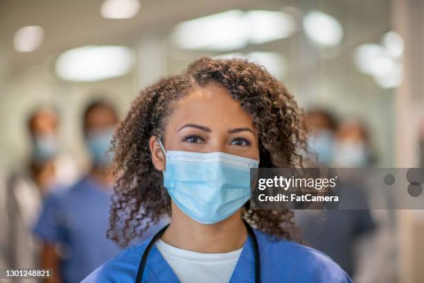 mooie vrouwelijke arts die achter haar masker glimlacht - masker stockfoto's en -beelden