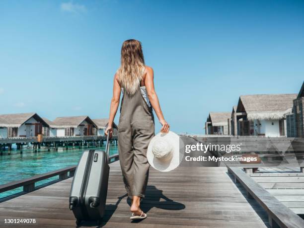 woman pulls trolley on wooden pier in tropical destination - return to paradise stock pictures, royalty-free photos & images