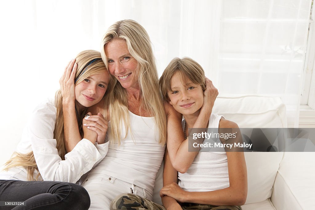 Smiling mother, daughter and son on a white couch.