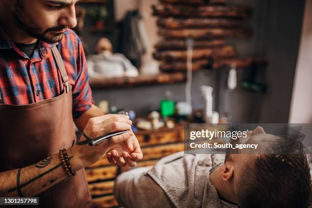 männlicher barbier rasiert den bart des kunden - male hair removal stock-fotos und bilder