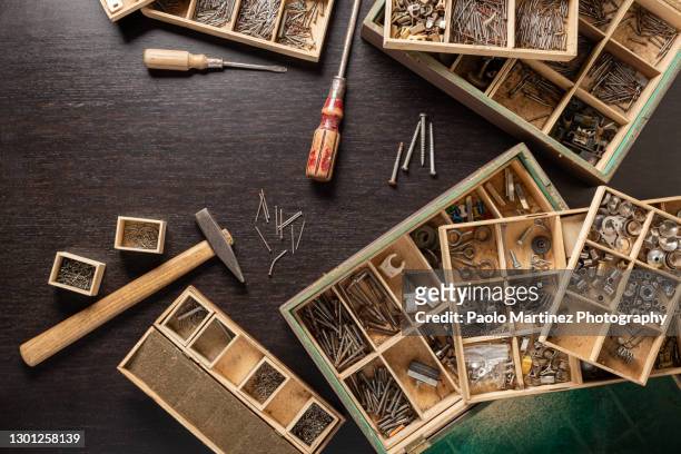 assorted nuts bolts nails and screws ordered into wooden case on black table - chiodo attrezzi da lavoro foto e immagini stock