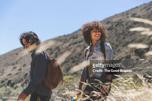 smiling young woman hiking with boyfriend on sunny day - trekker stock-fotos und bilder