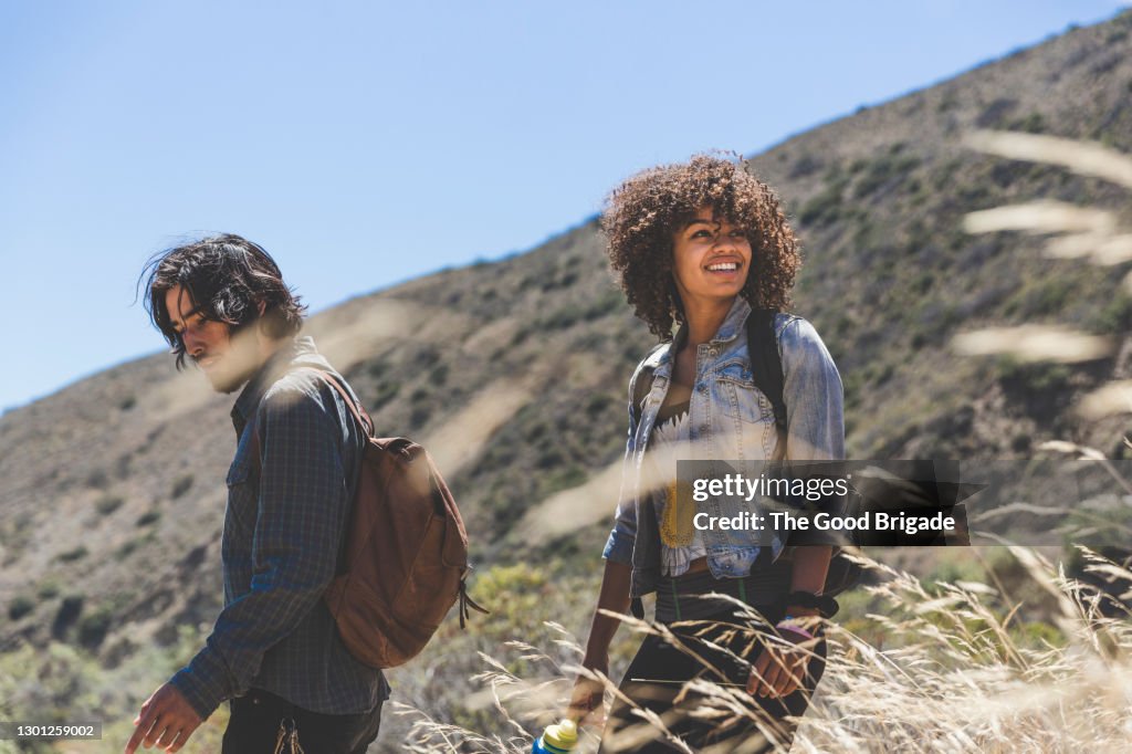 Smiling young woman hiking with boyfriend on sunny day