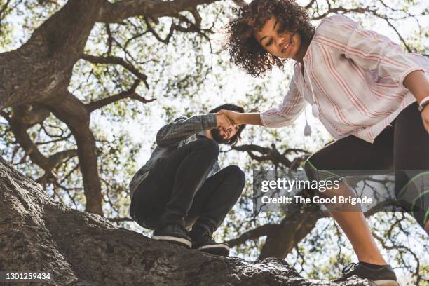 young couple climbing tree in forest - looking down photos et images de collection