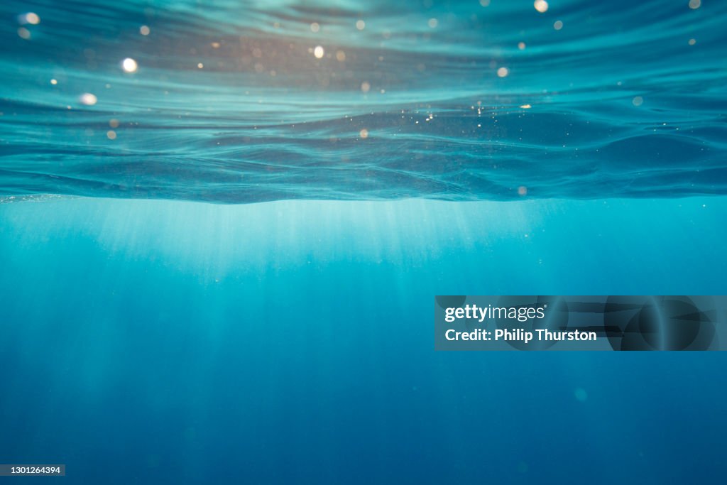 Clear blue aqua marine ocean with with light rays coming through water surface