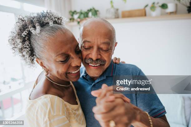 coppia senior spensierata che balla nel soggiorno - coppia anziana foto e immagini stock