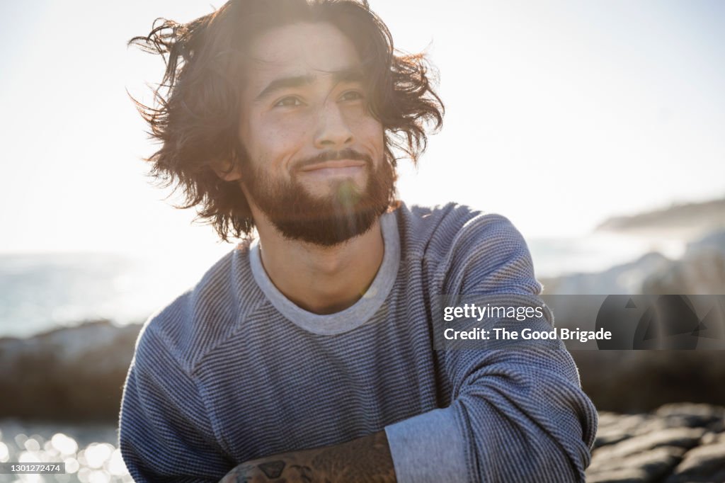 Portrait of young man at beach on windy day