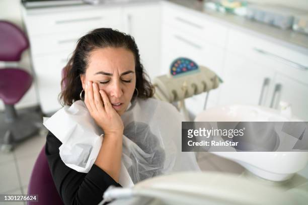 een jonge vrouw die kiespijn in de stoel van de tandarts heeft - parodontitis stockfoto's en -beelden