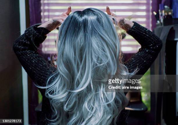 woman putting on a wig. - long gray hair stock pictures, royalty-free photos & images