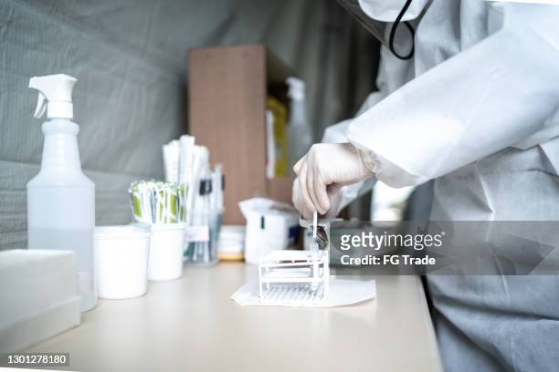 doctor cortando hisopo de algodón en un tubo de ensayo para pruebas de covid-19 - instrumento de la reacción en cadena de la polimerasa fotografías e imágenes de stock