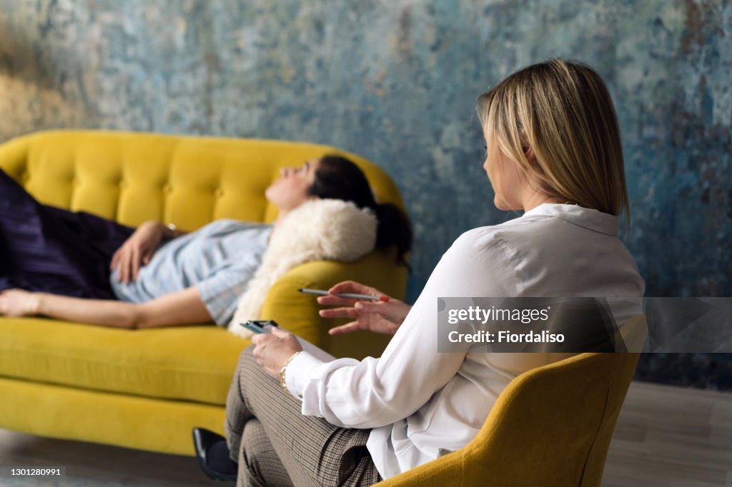 Positive blonde middle-aged woman psychologist talking to girl patient