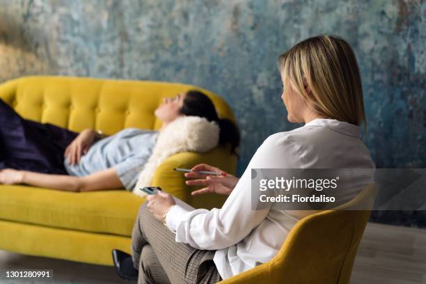 positive blonde middle-aged woman psychologist talking to girl patient - psychiatrist's couch stock pictures, royalty-free photos & images