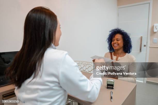 kvinnlig läkare levererar ett recept till patienten - dental office bildbanksfoton och bilder